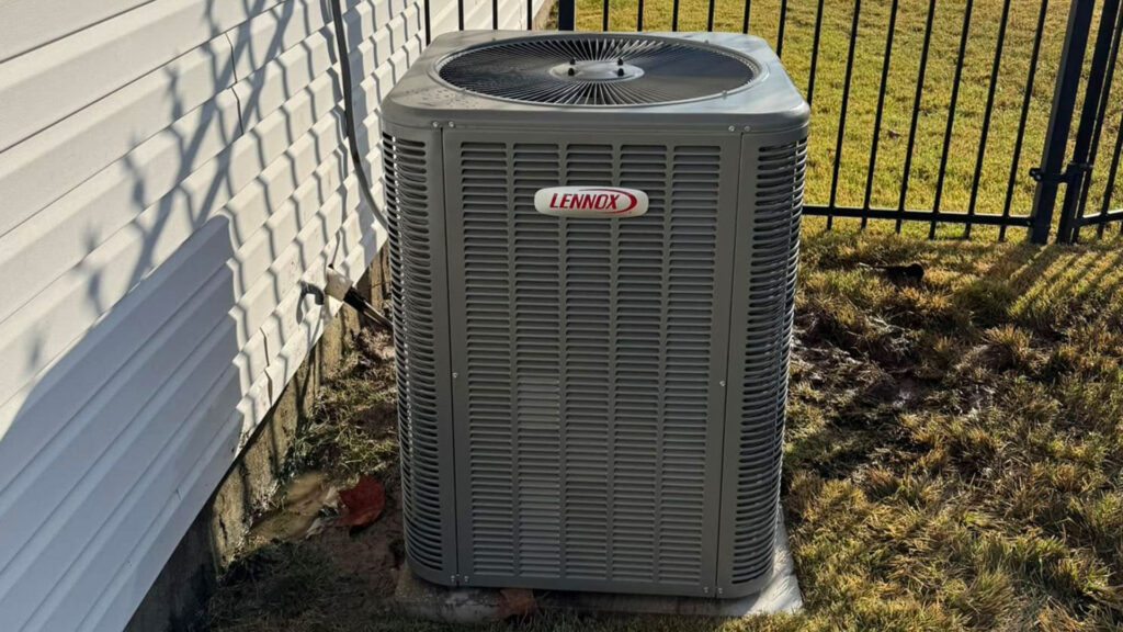 Lennox outdoor air conditioning condenser unit installed beside a house, next to a black iron fence